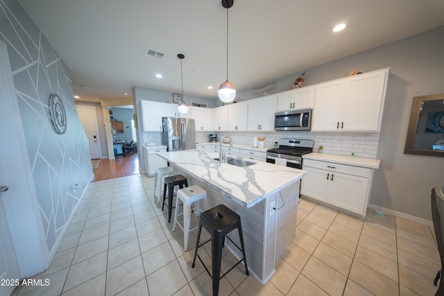 2361 N 212th Dr, Buckeye, AZ 85396 - kitchen with stainless steel appliances, tasteful backsplash, light tile patterned flooring, a breakfast bar, and white cabinets