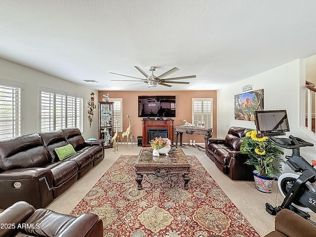 1350 E Racine Dr, Casa Grande, AZ 85122 - living room with a textured ceiling, a ceiling fan, visible vents, a glass covered fireplace, and light carpet