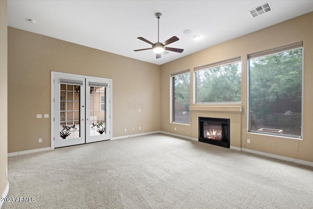 unfurnished living room featuring light carpet, french doors, and ceiling fan