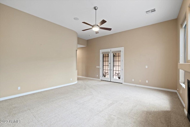 carpeted spare room featuring ceiling fan and french doors