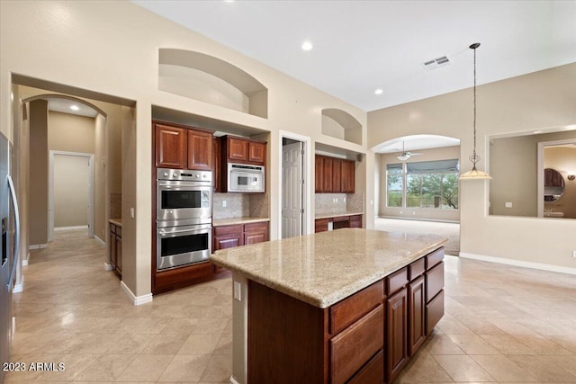 kitchen with ceiling fan, stainless steel appliances, backsplash, decorative light fixtures, and a kitchen island