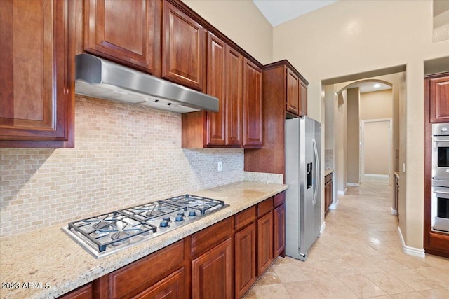 kitchen featuring light stone counters, light tile patterned floors, stainless steel appliances, and tasteful backsplash