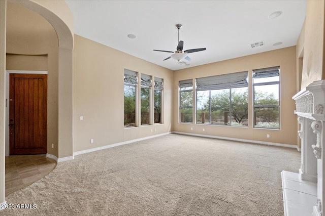 unfurnished living room featuring a fireplace, light carpet, and ceiling fan