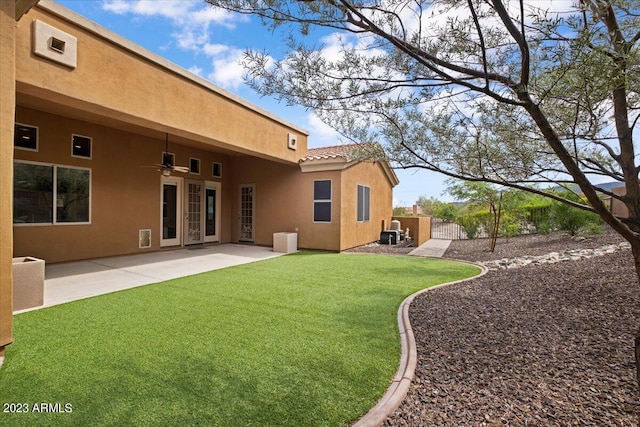 rear view of property featuring a lawn, a patio area, and ceiling fan