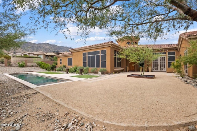 back of house featuring a mountain view, french doors, a fenced in pool, and a patio area