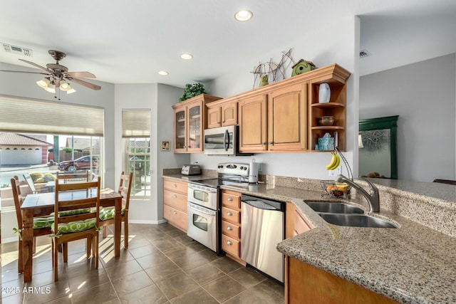 kitchen featuring light stone counters, ceiling fan, appliances with stainless steel finishes, and sink