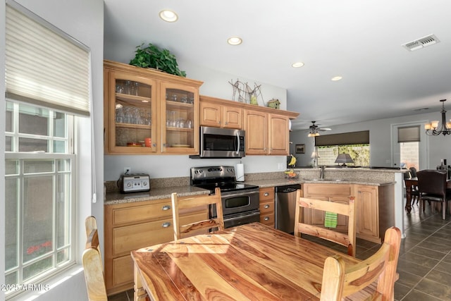 kitchen featuring appliances with stainless steel finishes, sink, dark tile patterned flooring, kitchen peninsula, and light stone countertops