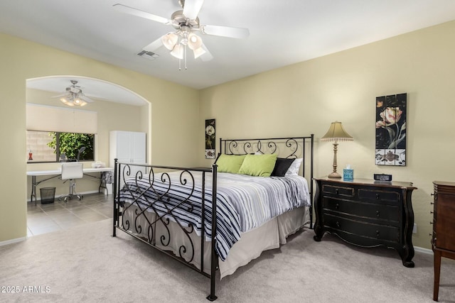 bedroom with ceiling fan, light colored carpet, and ensuite bathroom