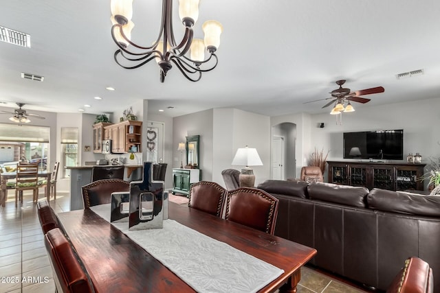 tiled dining room with ceiling fan with notable chandelier