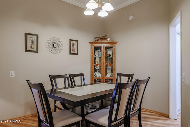 dining area featuring crown molding, light hardwood / wood-style flooring, and an inviting chandelier