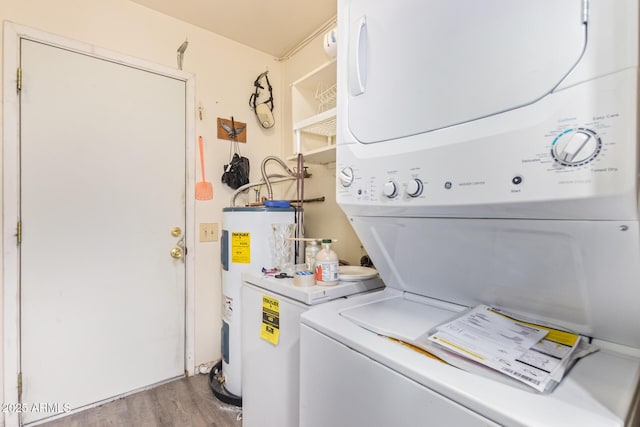 laundry room featuring laundry area, stacked washer and clothes dryer, wood finished floors, and electric water heater