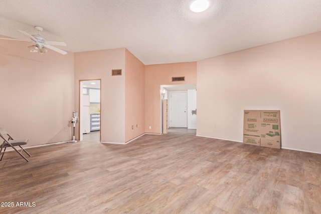 empty room with a ceiling fan, visible vents, a textured ceiling, and wood finished floors