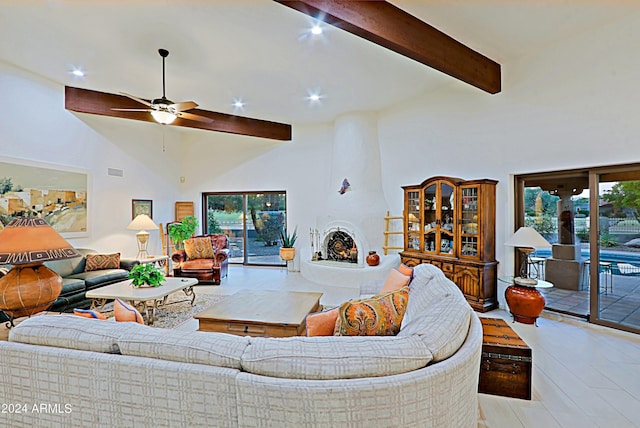 living room featuring a fireplace, high vaulted ceiling, beamed ceiling, ceiling fan, and light wood-type flooring