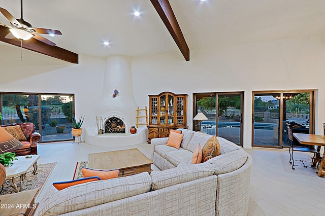 living room featuring a high ceiling, light wood-type flooring, ceiling fan, and beam ceiling