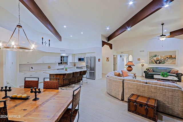 interior space with a large island, appliances with stainless steel finishes, white cabinetry, and beam ceiling