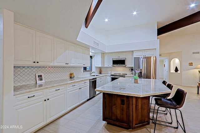 kitchen featuring a kitchen bar, stainless steel appliances, beamed ceiling, and a kitchen island