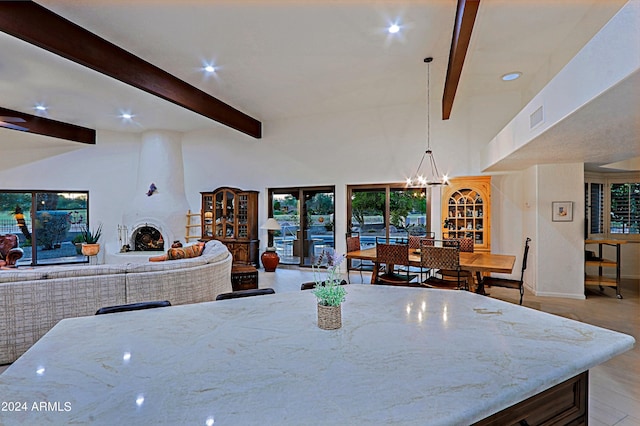 dining area with a large fireplace, beam ceiling, light hardwood / wood-style flooring, and a notable chandelier