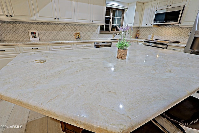 kitchen with stainless steel appliances, sink, light stone counters, tasteful backsplash, and a center island