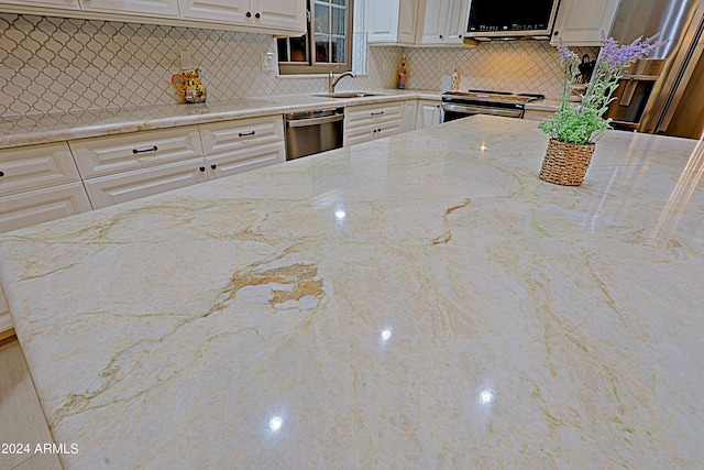 kitchen featuring tasteful backsplash, light stone countertops, appliances with stainless steel finishes, and sink