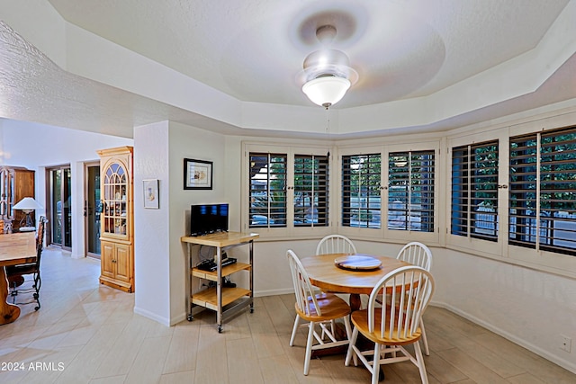 dining space with a textured ceiling, a raised ceiling, and ceiling fan