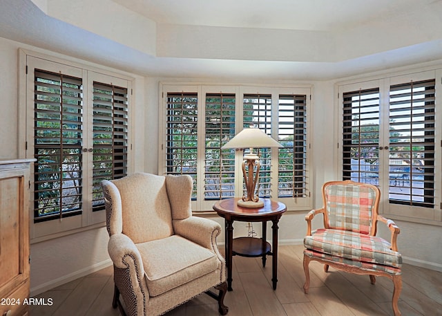 living area with wood-type flooring and a tray ceiling