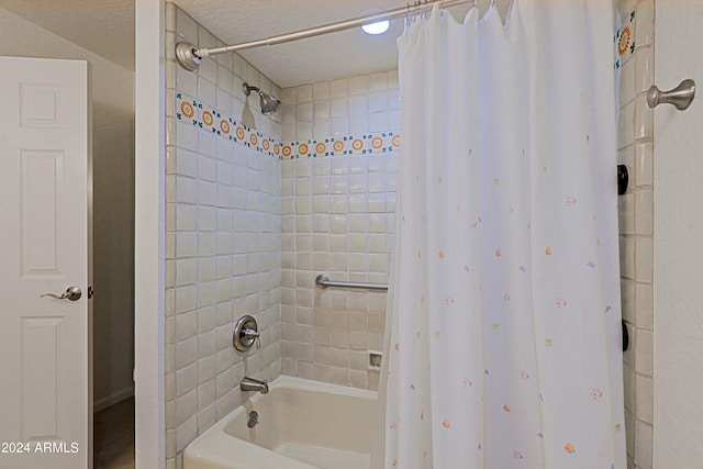 bathroom featuring a textured ceiling and shower / bathtub combination with curtain