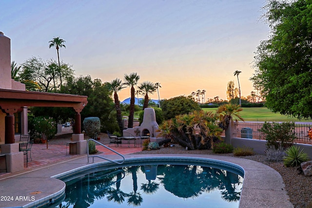 pool at dusk with a patio area