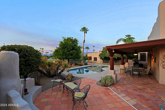 pool at dusk featuring a patio area