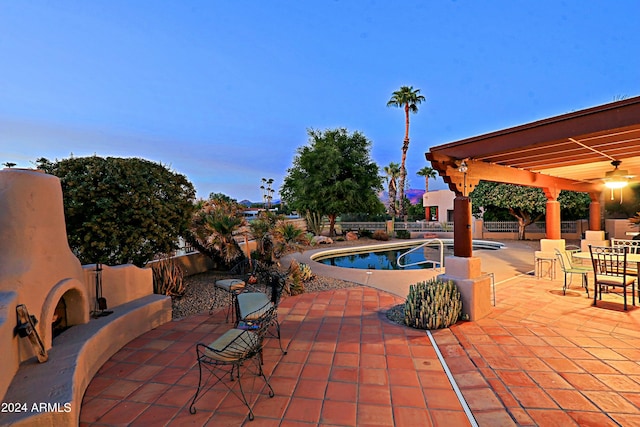 pool at dusk featuring a patio