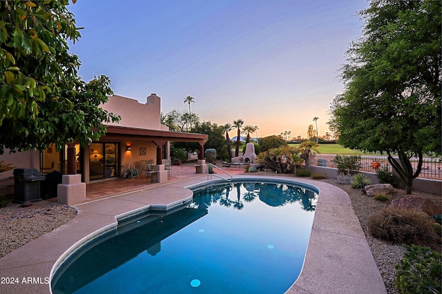 pool at dusk featuring a patio area