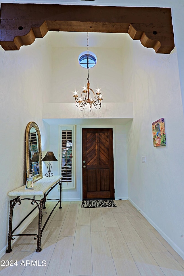 entrance foyer with a high ceiling, beamed ceiling, and a chandelier