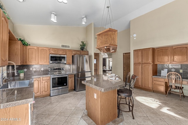 kitchen with appliances with stainless steel finishes, a center island, light tile patterned floors, high vaulted ceiling, and sink