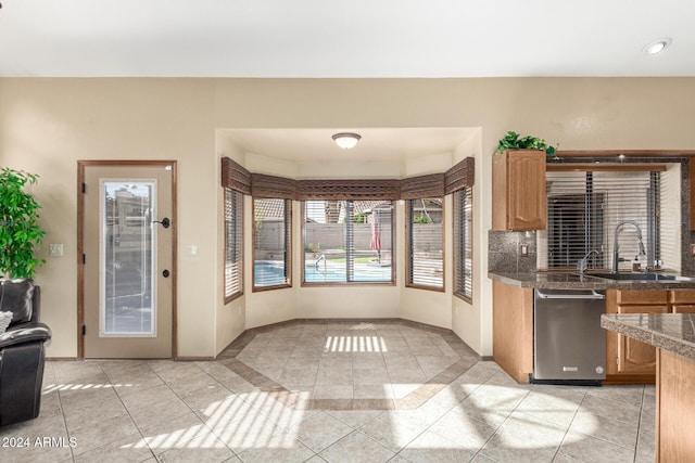 kitchen with sink, stainless steel dishwasher, and light tile patterned floors