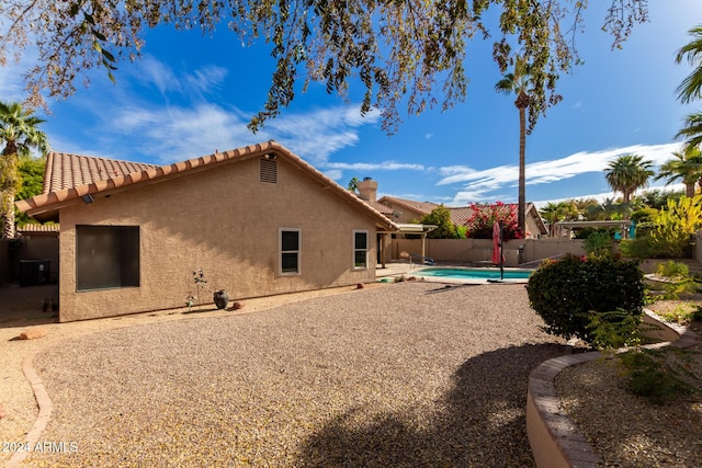 rear view of property with a patio area and a fenced in pool