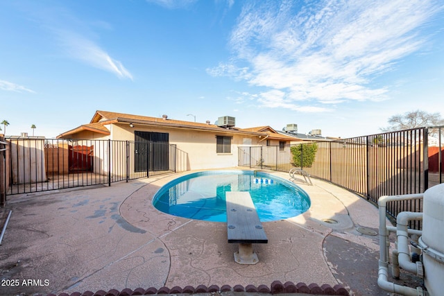 view of swimming pool with a patio, cooling unit, fence, a diving board, and a fenced in pool