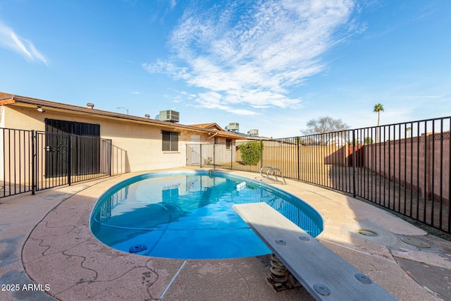 view of pool with a diving board, a fenced in pool, a fenced backyard, and central air condition unit