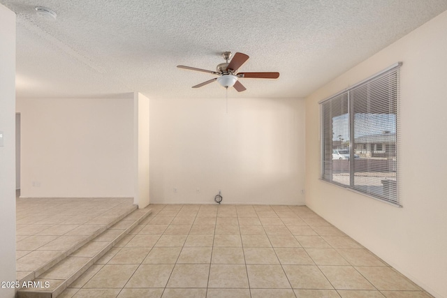 empty room featuring light tile patterned flooring, ceiling fan, and a textured ceiling