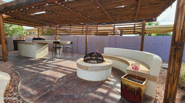 view of patio featuring an outdoor fire pit, outdoor dry bar, grilling area, fence, and exterior kitchen