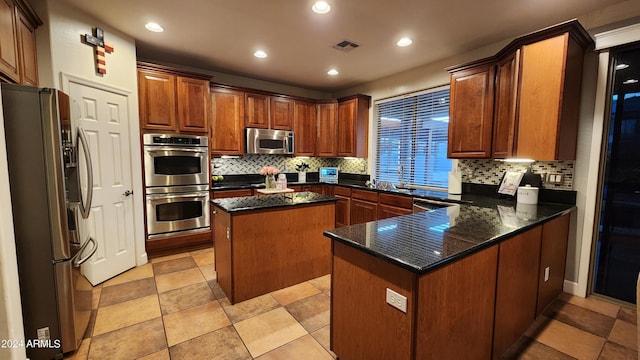 kitchen featuring stainless steel appliances, a peninsula, visible vents, backsplash, and a center island