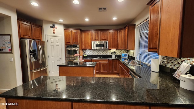 kitchen featuring a peninsula, a sink, a kitchen island, visible vents, and appliances with stainless steel finishes