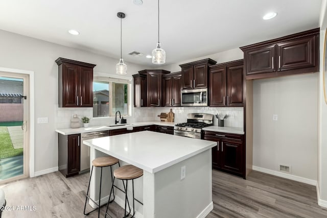 kitchen featuring pendant lighting, a kitchen island, stainless steel appliances, and light hardwood / wood-style floors