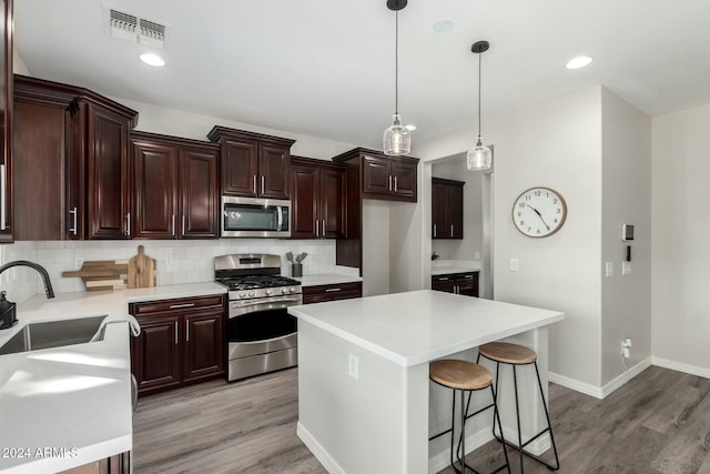 kitchen featuring backsplash, sink, stainless steel appliances, and hanging light fixtures