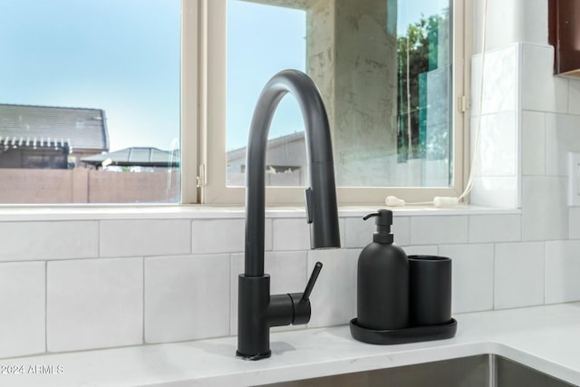 room details featuring decorative backsplash, light stone countertops, and sink