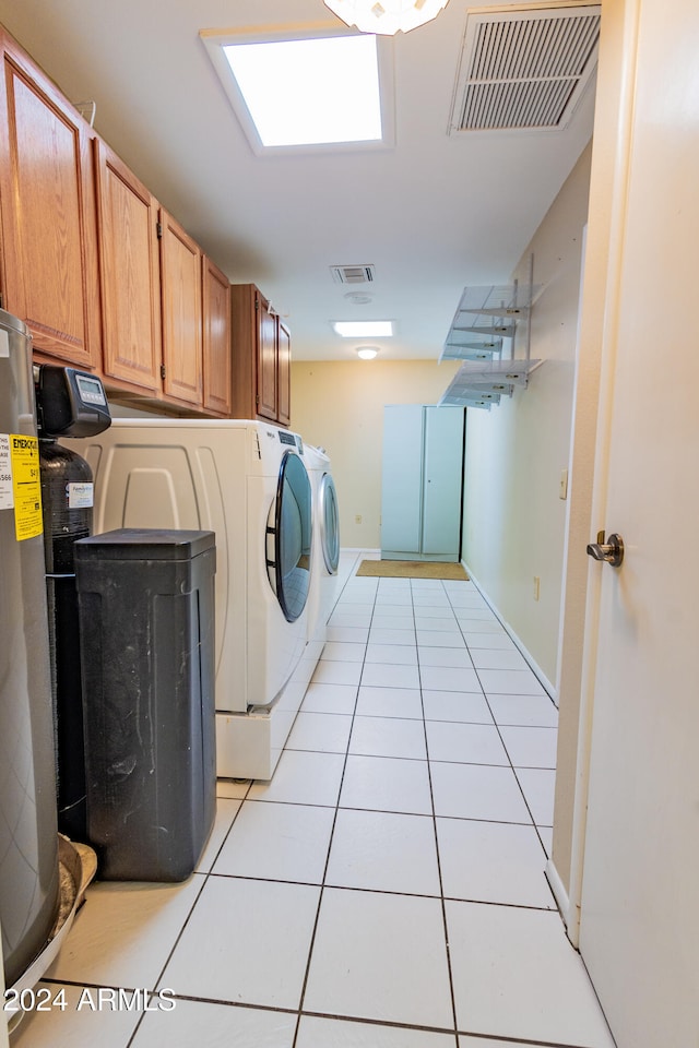 clothes washing area featuring cabinets, light tile patterned floors, and washing machine and dryer