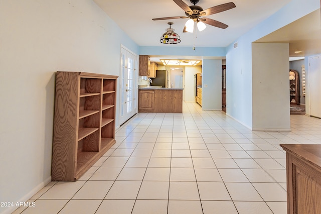 kitchen with kitchen peninsula, light tile patterned floors, stainless steel fridge, and ceiling fan