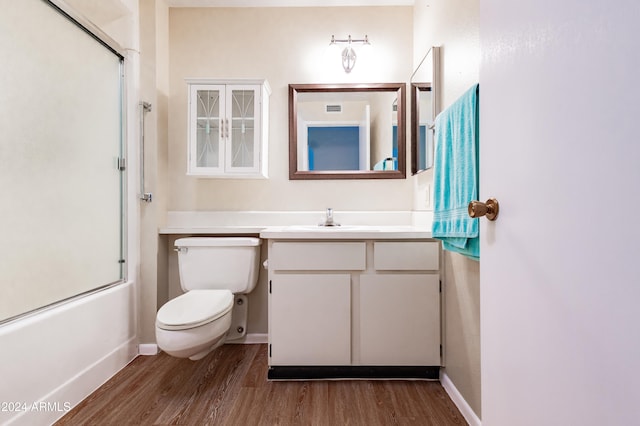 full bathroom featuring shower / bath combination with glass door, hardwood / wood-style floors, vanity, and toilet