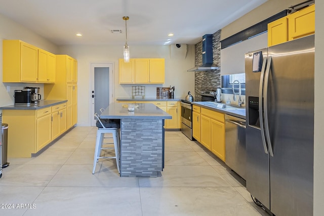 kitchen with appliances with stainless steel finishes, wall chimney exhaust hood, a kitchen island, pendant lighting, and sink