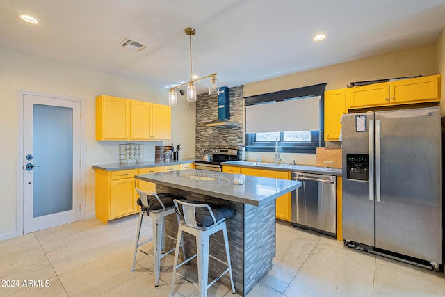 kitchen featuring sink, a kitchen bar, a kitchen island, wall chimney exhaust hood, and stainless steel appliances