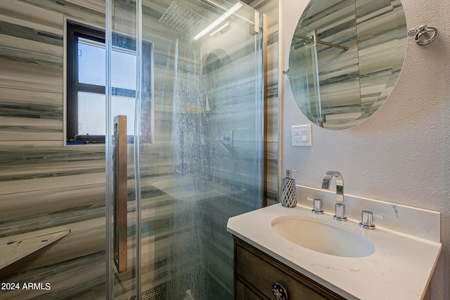 bathroom featuring a shower with shower door and vanity