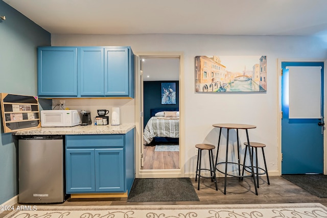 kitchen with blue cabinets, stainless steel refrigerator, and dark hardwood / wood-style flooring